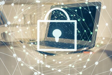 Double exposure of desktop with computer and lock icon hologram. Concept of data safety.