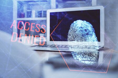 Computer on desktop in office with finger print drawing. Double exposure. Concept of business data security.の写真素材