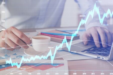 Forex graph with businessman working on computer in office on background. Concept of hardworking....