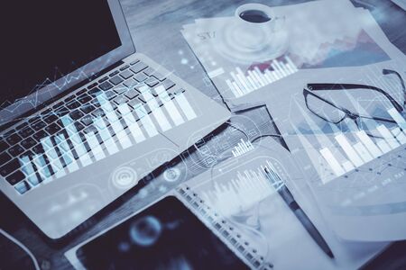 Stock market graph on background with desk and personal computer. Double exposure. Concept of financial analysis.の写真素材