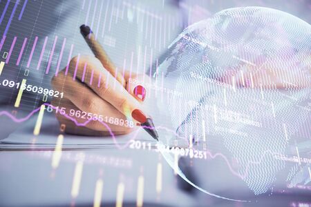 Double exposure of womans hands making notes with forex graph hologram. Concept stock market analysis.の写真素材