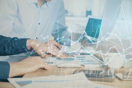 Multi exposure of chart with man typing on computer in office on background. Concept of hard work.