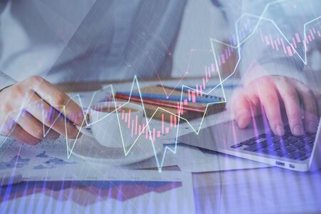Forex graph with businessman working on computer in office on background. Concept of hardworking....