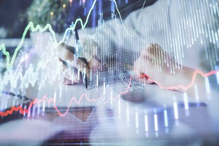 Financial forex graph displayed on hands taking notes background. Concept of research. Double exposureの写真素材