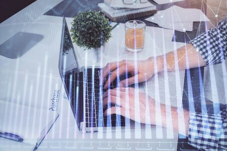 Double exposure of graph with man typing on computer in office on background. Concept of hard work.の写真素材