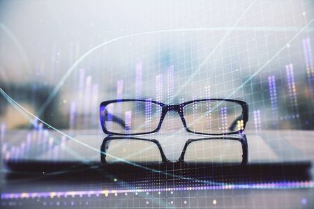 Financial graph hologram with glasses on the table background. Concept of business. Double exposure.の写真素材