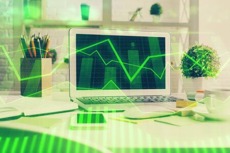 Stock market graph on background with desk and personal computer. Multi exposure. Concept of financial analysis.の写真素材
