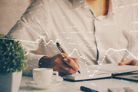Double exposure of mans hands writing notes of stock market with forex graph background. Concept of research and trading.の写真素材
