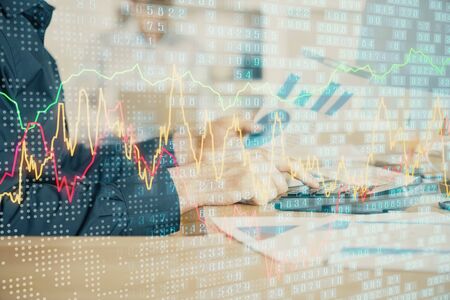 Double exposure of graph with man typing on computer in office on background. Concept of hard work....