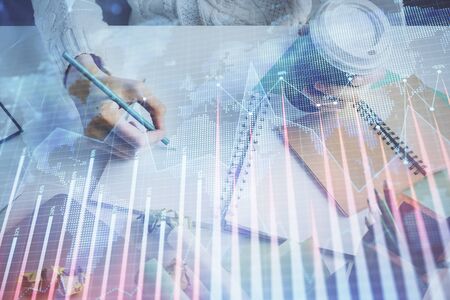 Financial forex graph displayed on hands taking notes background. Concept of research. Multi exposureの写真素材