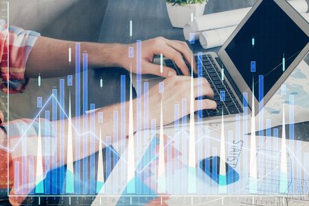 Double exposure of stock graph with businessman typing on computer in office on background. Concept...
