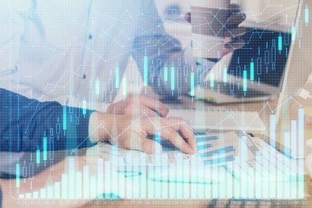 Multi exposure of chart with man typing on computer in office on background. Concept of hard work.