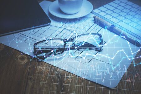 Financial chart hologram with glasses on the table background. Concept of business. Double exposure.