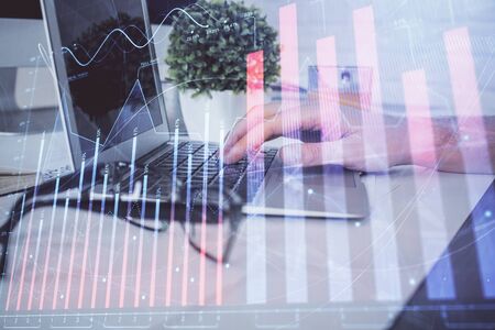 Multi exposure of graph with man typing on computer in office on background. Concept of hard work. Closeup.の写真素材