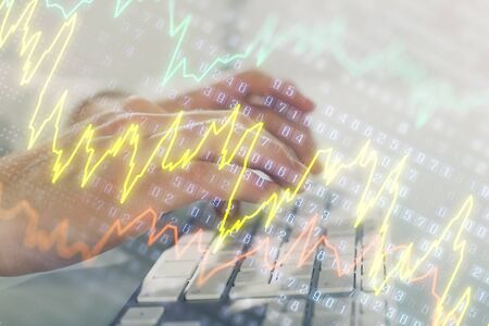Double exposure of graph with man typing on computer in office on background. Concept of hard work....