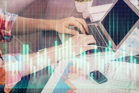 Double exposure of stock graph with businessman typing on computer in office on background. Concept of hard work.の写真素材