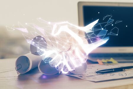 Desktop computer background in office and handshake hologram drawing. Double exposure. Pertnership concept.の写真素材