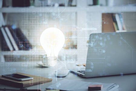 Computer on desktop in office with bulb icon hologram. Multi exposure. Concept of idea.の写真素材