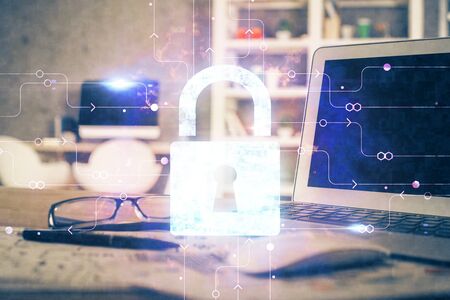 Double exposure of desktop with computer and lock icon hologram. Concept of data safety.