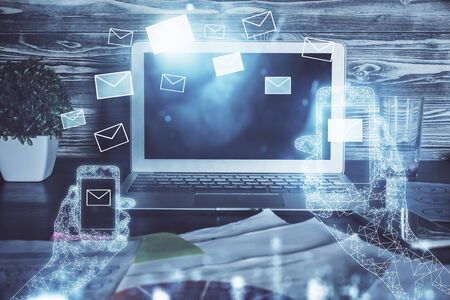 Desktop computer background in office and flying envelops hologram drawing. Multi exposure. Electronic mail concept.の写真素材