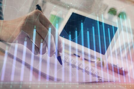 Financial forex graph drawn over hands taking notes background. Concept of research. Double exposureの写真素材