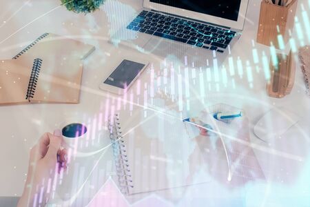 Hands writing information about stock market in notepad. Forex chart holograms in front. Concept of research. Multi exposureの写真素材