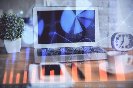 Stock market graph on background with desk and personal computer. Multi exposure. Concept of financial analysis.の写真素材