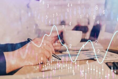 Double exposure of man's hands writing notes of stock market with forex graph. Side View. Concept of research and trading.の写真素材