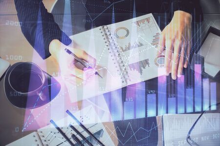 Multi exposure of hands making notes with forex chart huds. Stock market concept.の写真素材