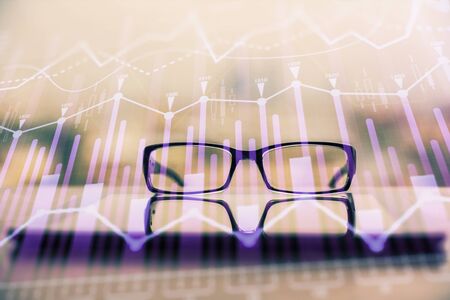 Financial graph hologram with glasses on the table background. Concept of business. Double exposure.の写真素材