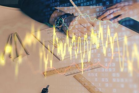 Double exposure of man's hands writing notes of stock market with forex graph background. Concept of...