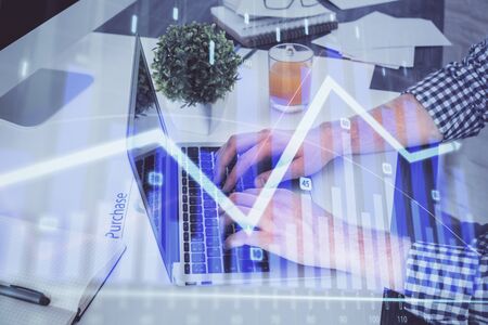 Double exposure of graph with man typing on computer in office on background. Concept of hard work.の写真素材