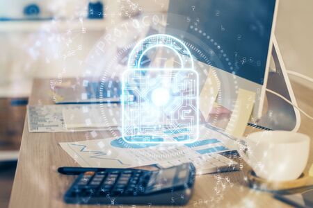 Double exposure of desktop with computer and lock icon hologram. Concept of data safety.