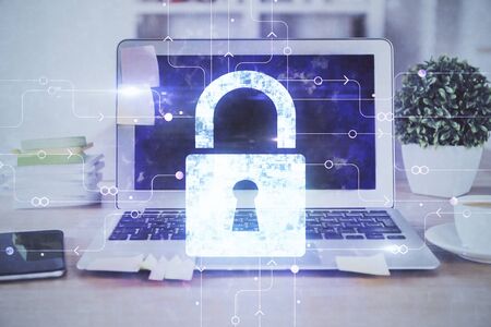Double exposure of desktop with computer and lock icon hologram. Concept of data safety.
