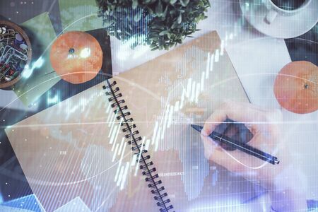 Forex chart hologram on hand taking notes background. Concept of analysis. Double exposureの写真素材