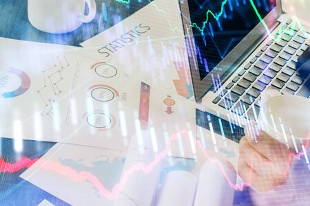 Double exposure of stock graph with businessman typing on computer in office on background. Concept...