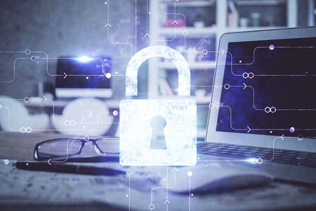 Double exposure of desktop with computer and lock icon hologram. Concept of data safety.