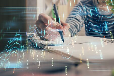 Financial forex graph drawn over hands taking notes background. Concept of research. Double exposure