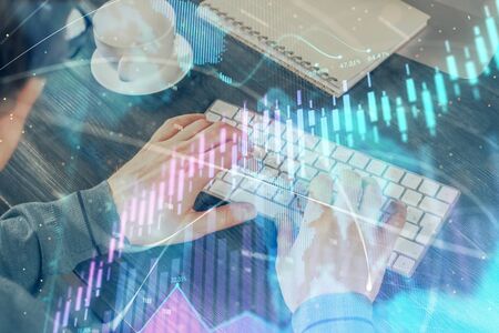 Double exposure of graph with man typing on computer in office on background. Concept of hard work.