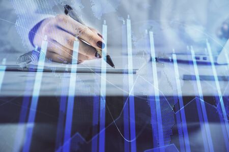 Double exposure of womans hands making notes with forex graph hologram. Concept technical analysis.の写真素材