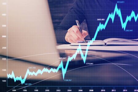 Double exposure of businessmans hands with laptop and stock market graph background. Concept of...