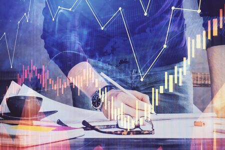 Double exposure of man writing on paper with forex graph. Concept of research and trading.