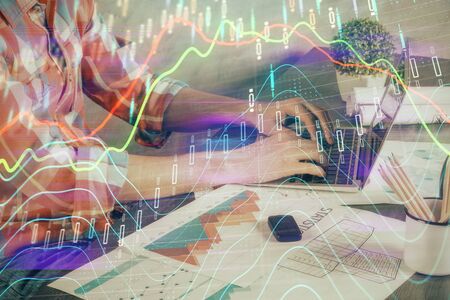 Double exposure of stock graph with businessman typing on computer in office on background. Concept...