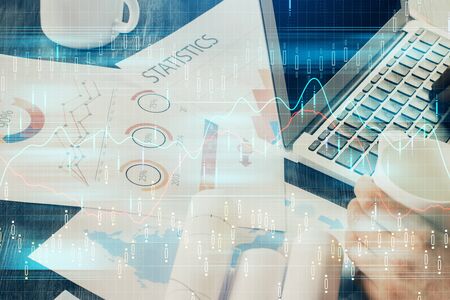 Double exposure of stock graph with businessman typing on computer in office on background. Concept...