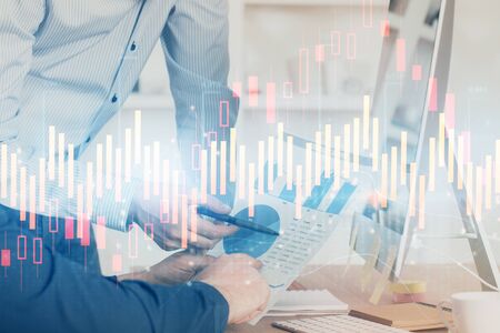 Double exposure of chart with businessman typing on computer in office on background. Concept of...