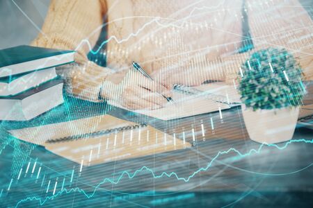 Forex graph on hand taking notes background. Concept of research. Double exposure