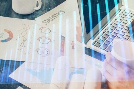 Double exposure of stock graph with businessman typing on computer in office on background. Concept...
