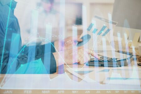Double exposure of graph with man typing on computer in office on background. Concept of hard work....
