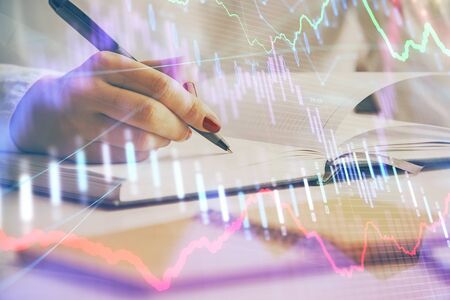 Multi exposure of womans hands making notes with forex graph hologram. Concept stock market...