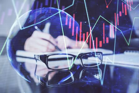Forex chart hologram on hand taking notes background. Concept of analysis. Double exposureの写真素材